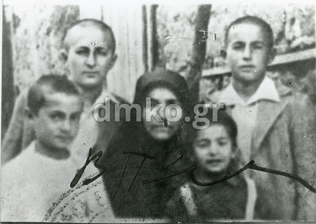 Η χήρα Αικατερίνη Δημοπούλου, σύζυγος του εκτελεσθέντα Δήμου Δημόπουλου, εικονίζεται με τα τέσσερα ορφανά παιδιά της, τον Γιώργο, τον Σπύρο, τον Άδωνι και τη Μαρία. 